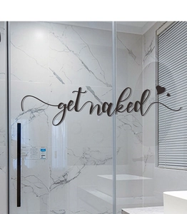 Detailed view of GET NAKED wall sticker with heart accents on bathroom glass door