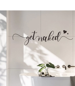Detail of black cursive Get Naked wall sticker with heart accents on bathroom tiles