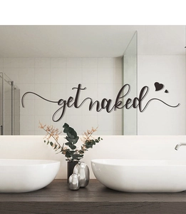 Close-up of black Get Naked cursive wall decal with hearts on a bathroom mirror