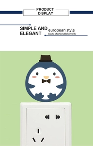Detail eines Cartoon-Pinguin-Steckdosenaufklebers mit Hut auf einer weißen Steckdose