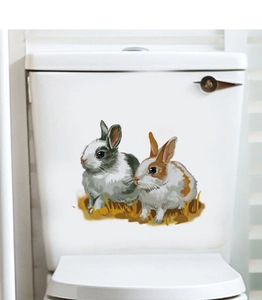 Détail de deux autocollants de lapin réalistes appliqués sur un réservoir de WC blanc