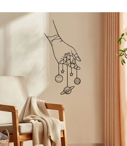 Creative black line wall sticker featuring hands holding planets in a cozy bedroom setting