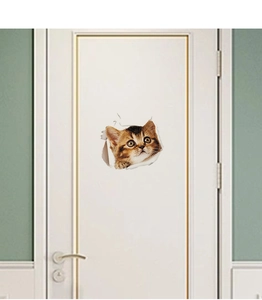 Detail of 3D kitten wall sticker peeking through torn paper on a white room door