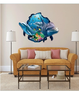 3D ocean dolphins wall decal with tropical fish shown above a yellow sofa in a living room