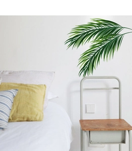 Détail de stickers muraux feuilles de palmier tropicales dans une chambre moderne et épurée