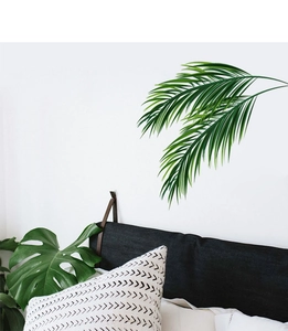 Détail de deux autocollants muraux de feuilles de palmier tropicales sur un mur de chambre