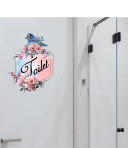 Détail d'un sticker mural floral décoratif avec un oiseau bleu et texte Toilet sur porte blanche