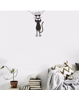 Detail of funny black climbing cat wall sticker above a modern sofa and books