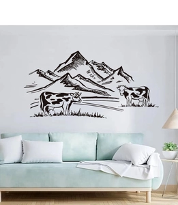 Minimalist farmhouse wall decal with black cows and mountains over a modern sofa