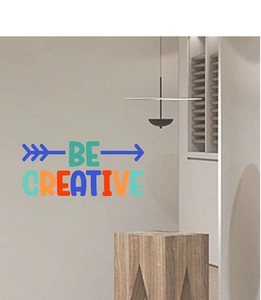 Vue détaillée du sticker mural coloré Be Creative sur un mur de salon gris minimaliste
