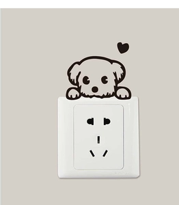 Close-up of a cartoon dog and heart sticker applied above a white wall power outlet