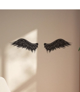 Detail of symmetrical black wing wall decals with fine feather textures on a beige wall