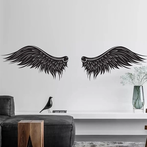 Minimalist hand-drawn black angel wings wall stickers on white wall above a modern sofa