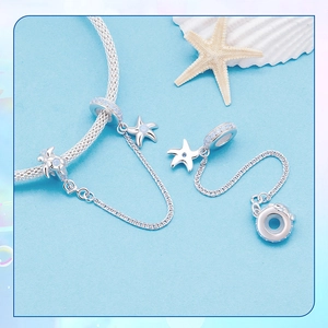 Macro detail of S925 sterling silver ocean safety chain with starfish and turtle charms