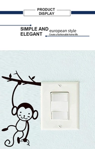 Détail d'un sticker mural singe sur branche à côté d'un interrupteur double