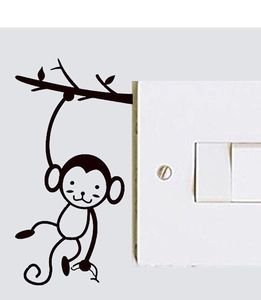 Détail d'un autocollant mural singe noir mat sur une branche près d'un interrupteur