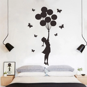 Détail d'un sticker mural noir de fille aux ballons au-dessus d'un lit de chambre