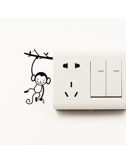 Détail du sticker mural singe sur branche posé sur un interrupteur mural blanc chic