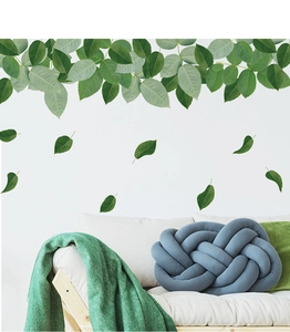 Detailed view of green leaf wall stickers with a textured blue knot pillow in a home setting