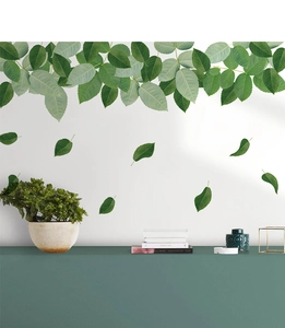 Detail of green leaf wall stickers on white wall creating a fresh indoor atmosphere