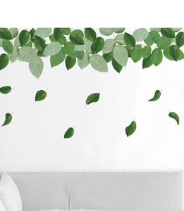 Detail of minimalist green leaf wall stickers above a sofa creating a natural home atmosphere