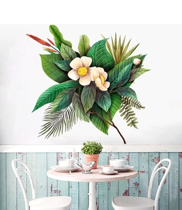 Dettaglio di adesivi murali con foglie tropicali e fiori bianchi in una sala da pranzo