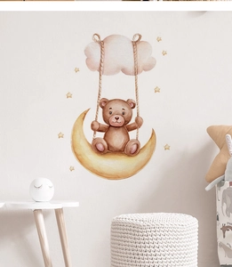 Detail of watercolor teddy bear on moon wall sticker in a cozy nursery room setting