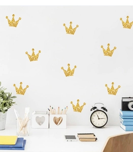 Close-up of golden glitter crown wall stickers in a cozy kids bedroom decor setting