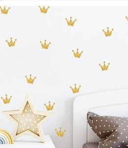 Close-up of golden glitter crown wall stickers in a cozy nursery room setting