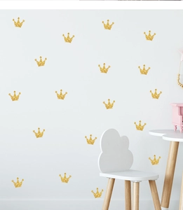 Close-up of golden glitter crown wall stickers on a clean white wall for nursery decor