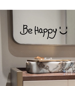 Close-up of 'Be Happy' mirror wall decal applied on a surface near jewelry boxes
