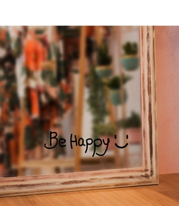 Close-up of Be Happy wall sticker with smile icon on a vintage wooden mirror frame