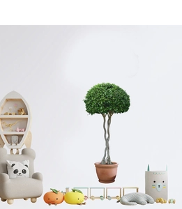 Détail d'une plante verte artificielle avec tronc tressé dans un pot en céramique rouge