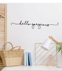 Detailed view of hello gorgeous wall decal on white wall with Nordic home decor accents