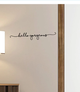Detailed view of hello gorgeous vinyl wall decal in black cursive font on beige wall