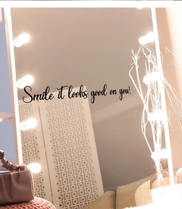 Détail du sticker mural Smile it looks good on you sur un miroir de maquillage éclairé