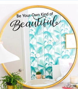 Détail du sticker Be Your Own Kind of Beautiful sur un miroir mural rond doré élégant