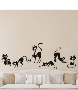 Detail showing six black cartoon cat vinyl wall decals on a light beige living room wall