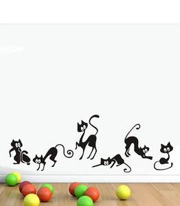 Detail of six black silhouette cat wall decals on white wall near wooden floor décor