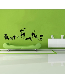 Detail view of six black cartoon cat wall decals in various poses on a green wall