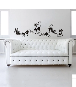 Detailed close-up of five cartoon black cat wall decals on a clean white living room wall
