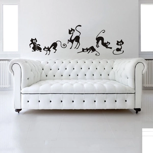 Minimalist black cat wall stickers silhouettes on white wall above a modern sofa