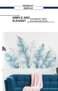 Detail of Nordic blue palm leaves wall decals with gold lines above a blue fabric sofa