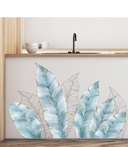 Detail of tropical leaf wall stickers with gold accents in a modern minimalist kitchen
