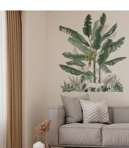 Detail of tropical banana tree wall decals with a white cat near a modern gray sofa