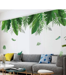 Detail of tropical PVC wall stickers featuring green monstera and palm leaves on a living room wall