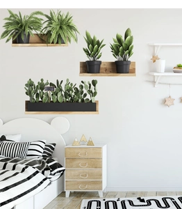 Three creative potted plant wall stickers on a white wall above a wooden cabinet