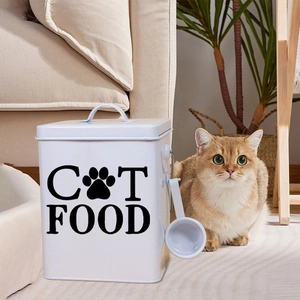 Close-up of white metal cat food storage bin with lid, scoop and black lettering