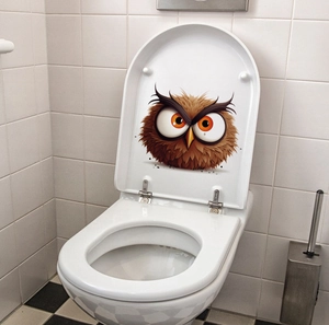 Close-up of cute cartoon owl sticker with orange eyes on a white toilet lid