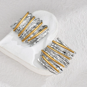 Minimalist gold and silver two-tone earrings with textured waves and linear metal details